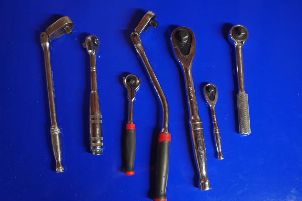 Assorted ratchet wrenches laid out on a blue background.